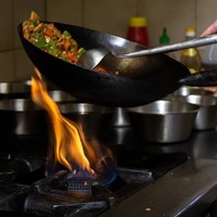 traditionelles Kochen in Wok auf großer Flamme